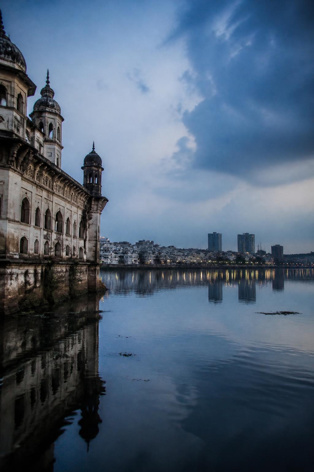 Contemporary Hyderabad spanning both sides of the Musi River at dusk.