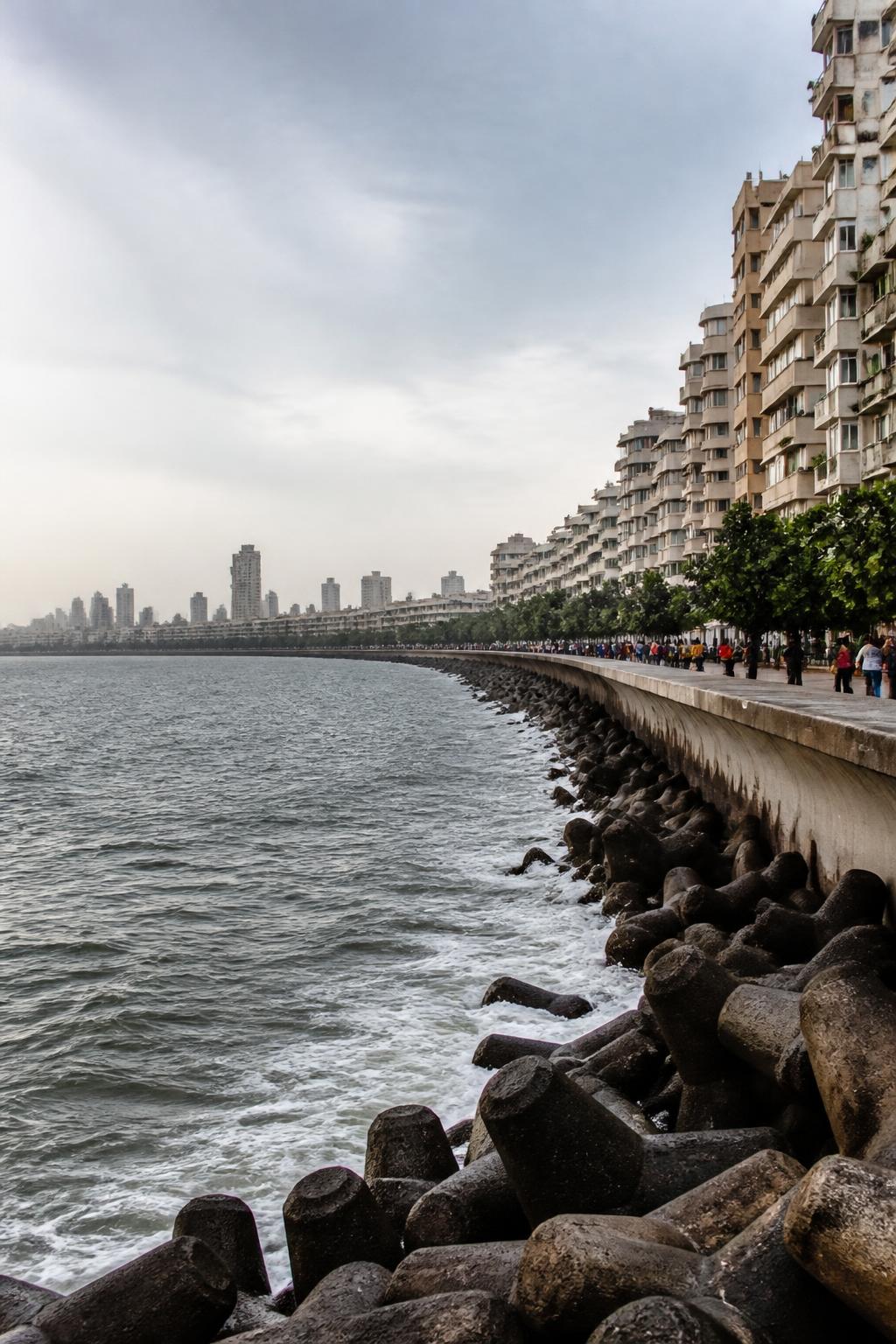People walking along Marine Drive beside Art Deco buildings and the sea.